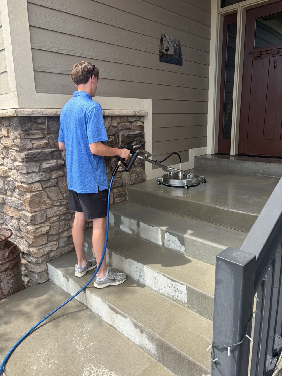 Technician surface-cleaning a home’s front porch steps